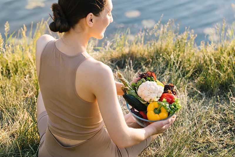 Mujer en la naturaleza con bol de verduras